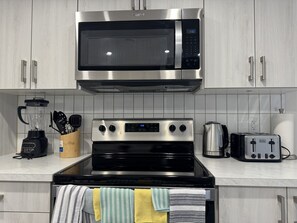 A modern kitchen with stainless steel appliances, including a microwave, stove, and toaster. - Paradise in Glenridding (Edmonton)