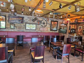 A restaurant interior with wooden tables, booths, and a stone wall with various signs.