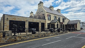A building with a stone facade, multiple windows, and outdoor seating areas.