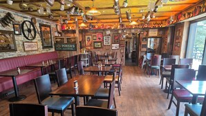 A restaurant interior with wooden tables and booths, hanging lights, and various wall decorations. - The rusty Mackerel  (DL)