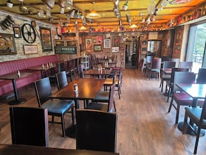 A restaurant interior with wooden tables and booths, hanging lights, and various wall decorations. - The rusty Mackerel  (DL)
