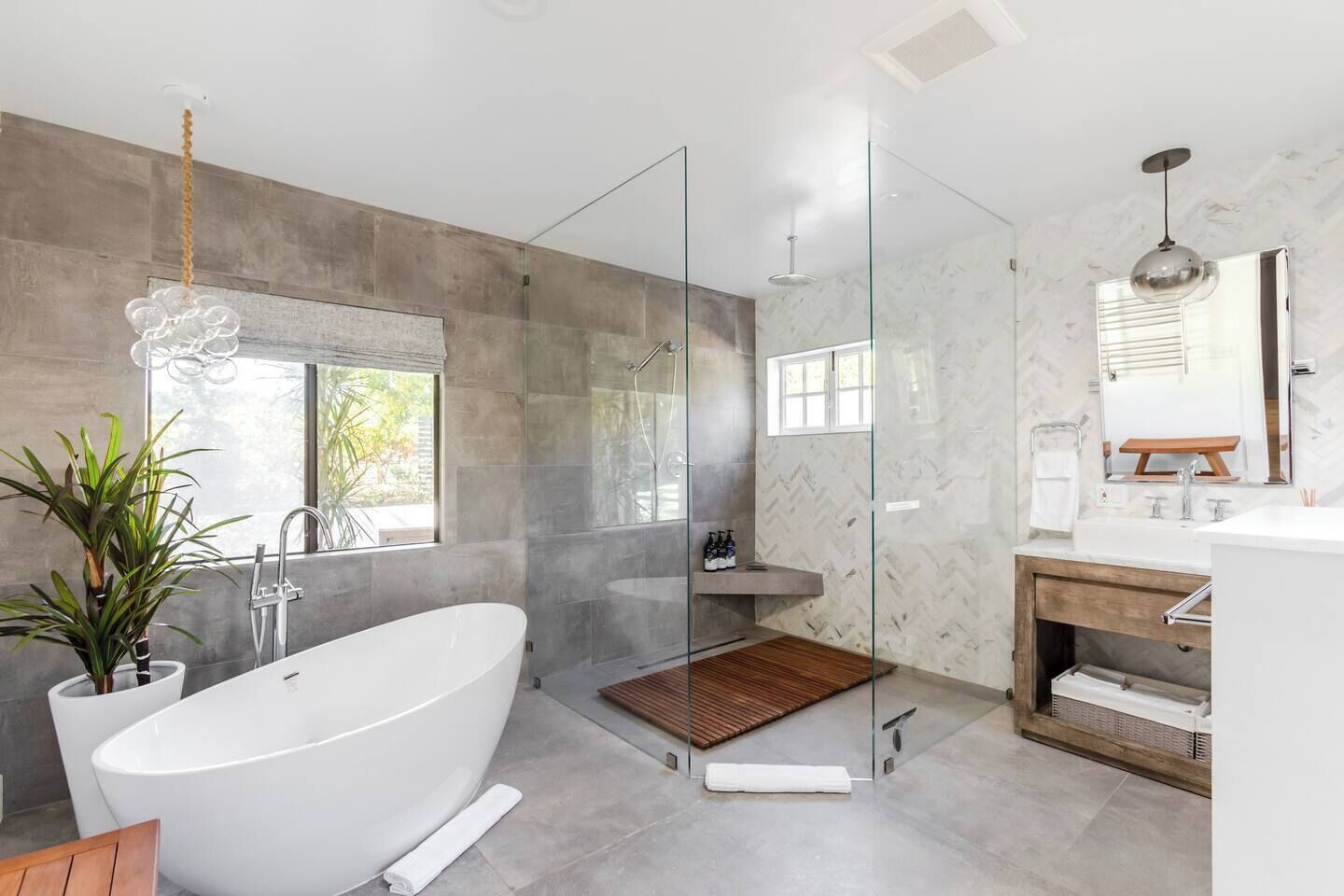 A modern bathroom with a freestanding bathtub, a glass-enclosed shower, and a vanity with a mirror.