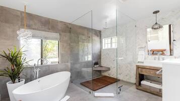A modern bathroom with a freestanding bathtub, a glass-enclosed shower, and a vanity with a mirror.