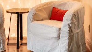 A room with a covered chair, a small table, and a curtain with lights. - Serene Nashville Executive and Family Retreat Minutes to 12 South & Green Hills (Nashville)