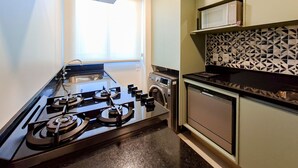 Une cuisine compacte équipée d’une cuisinière à gaz, d’un four encastré, d’un four à micro-ondes et d’un lave-vaisselle.