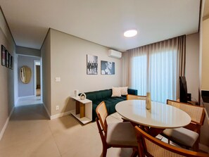 Ein modernes Wohnzimmer mit einem runden Esstisch, einem grünen Sofa und einem Flachbildfernseher.