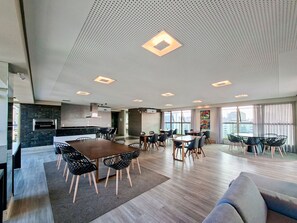 A modern kitchen with a built-in oven and a dining area with a large table and chairs. - Apto c Garagem Piscina e Sauna no Savassi (Belo Horizonte)