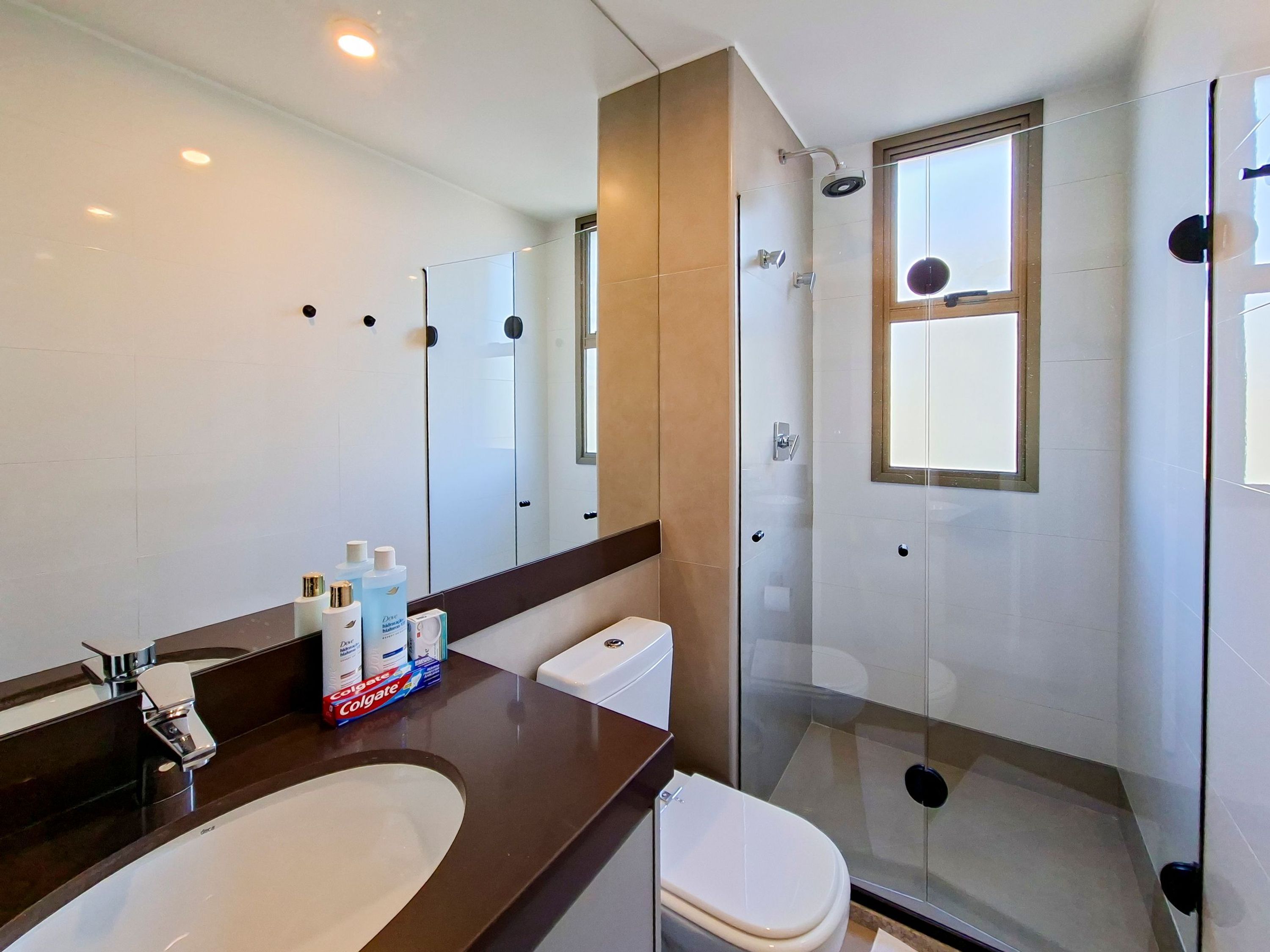 A modern bathroom with a large mirror, a shower enclosure, and a toilet.