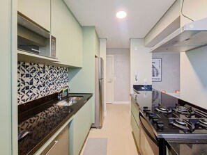 Eine moderne Küche mit schwarzem Arbeitsplatz, Edelstahlgeräten und einer gemusterten Spritzschutzwand.