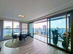 Ein modernes Wohnzimmer mit großem Fenster, einem runden Tisch mit Stühlen und Blick auf die Stadt.