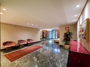 Eine Hotelhalle mit Marmorboden, einem roten Teppich und einer Rezeption mit Zimmerpflanze.