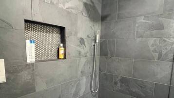 Ducha con cabezal de ducha de mano y zona de ducha con mampara de vidrio.