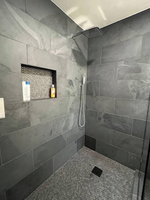 Ducha con cabezal de ducha de mano y zona de ducha con mampara de vidrio.