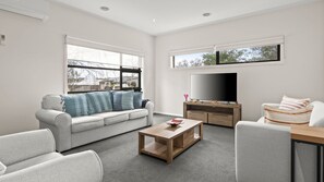 A modern living room with a sofa, coffee table, and TV.