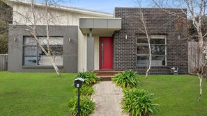A modern two-story house with a red door, a brick facade, and a well-maintained lawn. - Seamist Retreat - A relaxing coastal escape designed for easy holiday living (Indented Head)