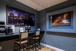 Zona de bar con vista a la ciudad, una máquina de café y dos taburetes.