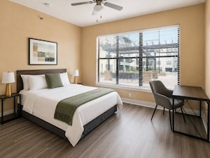 A bedroom with a bed, bedside lamps, a desk, and a chair.