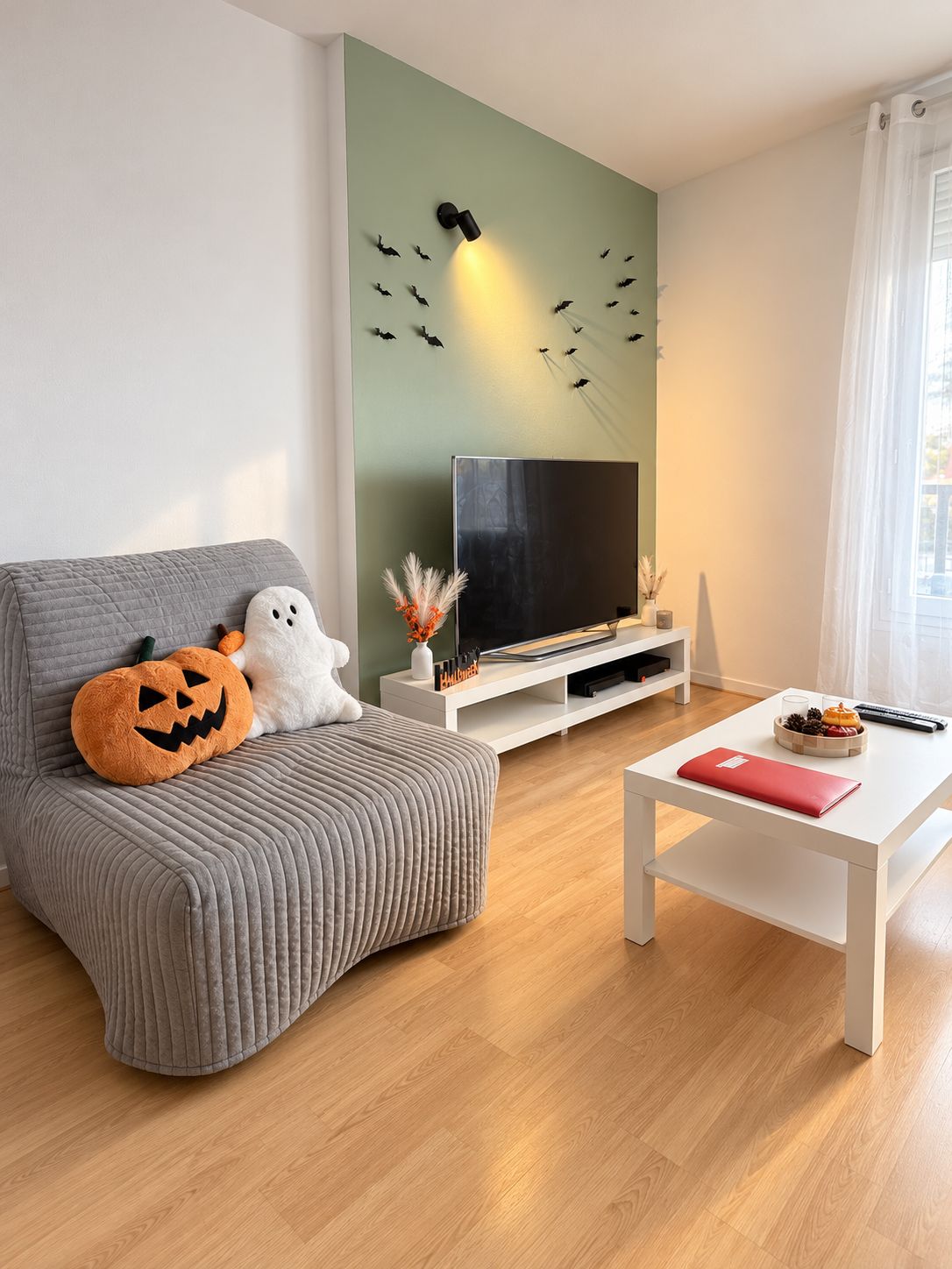 A modern living room with a grey sofa, a flat-screen TV, and Halloween-themed decorations.