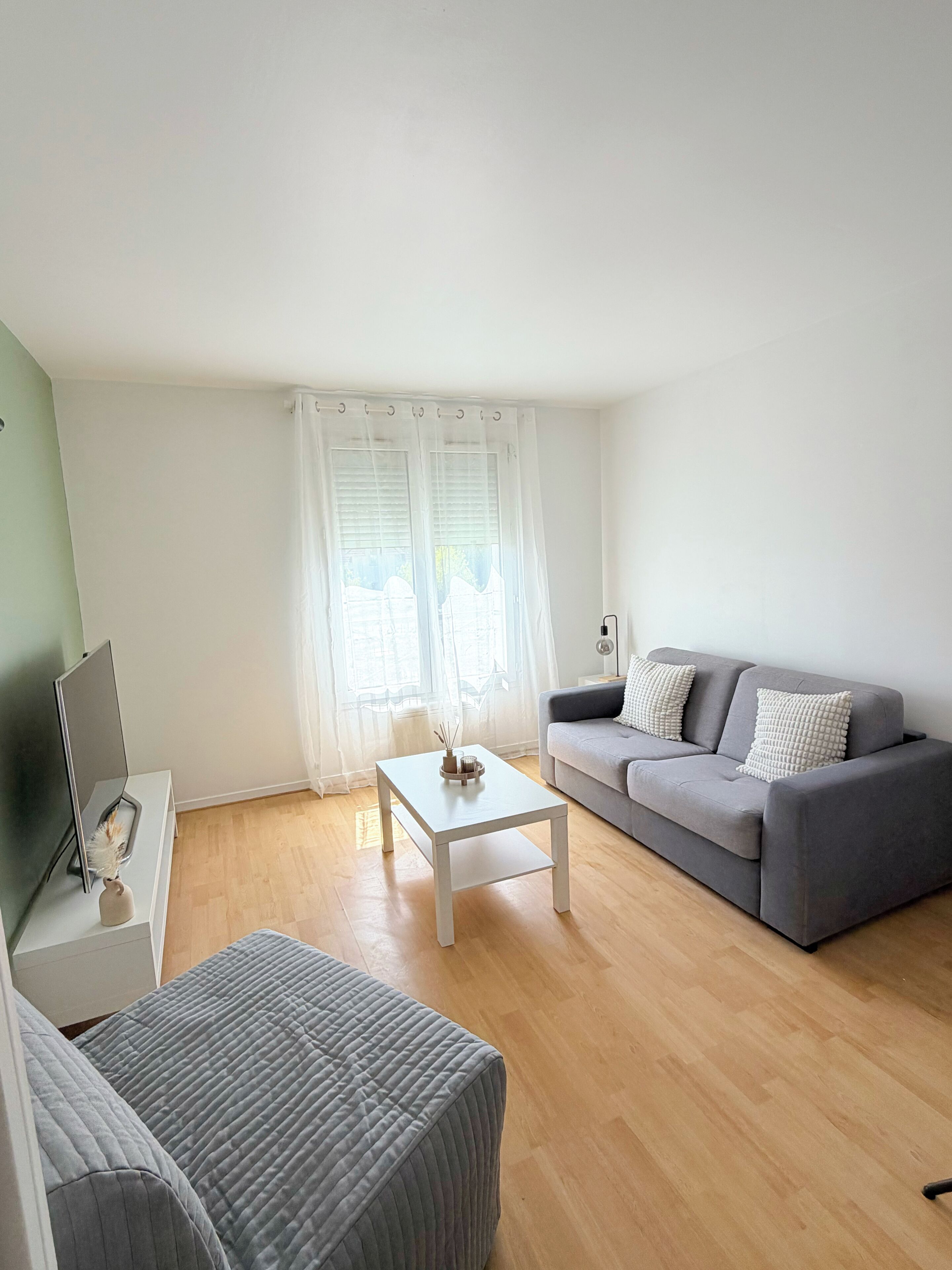 A modern living room with a grey sofa, a white coffee table, and a grey ottoman.
