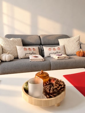 Ein graues Sofa mit Zierkissen, die Kürbisse zeigen und den Schriftzug 'pumpkin' tragen.