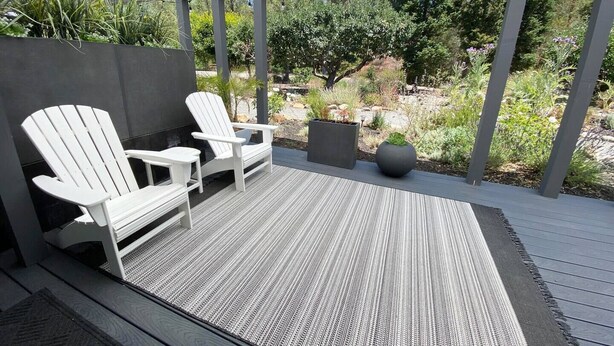 A covered outdoor seating area with Adirondack chairs and a textured rug.