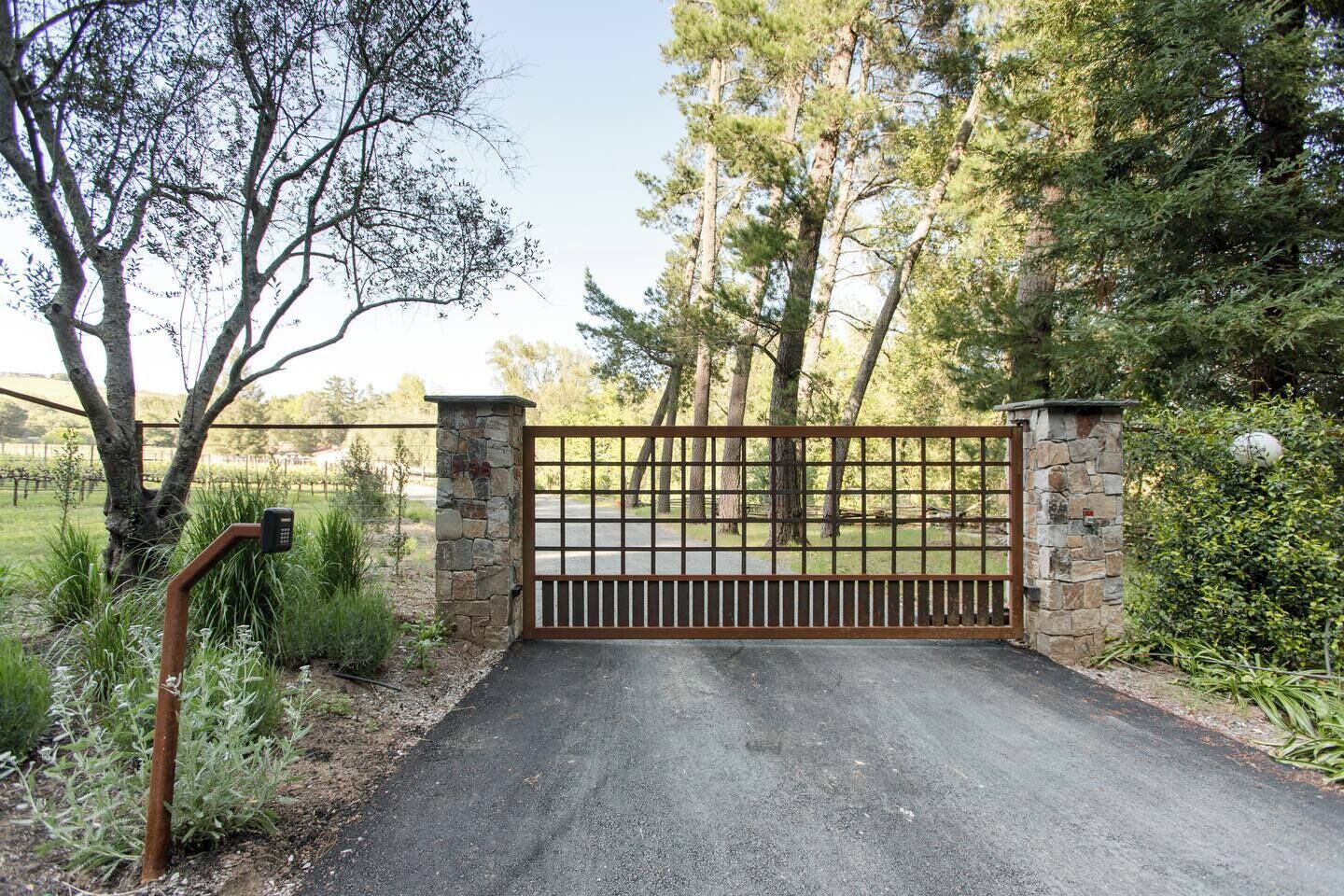 A gated driveway leading to a property surrounded by trees and greenery.