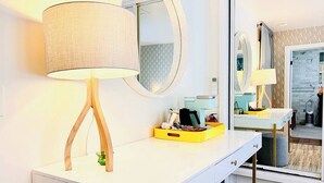A modern bathroom with a white vanity, a round mirror, and a lamp with wooden legs.