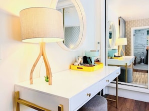 A modern bathroom with a white vanity, a round mirror, and a lamp with wooden legs.