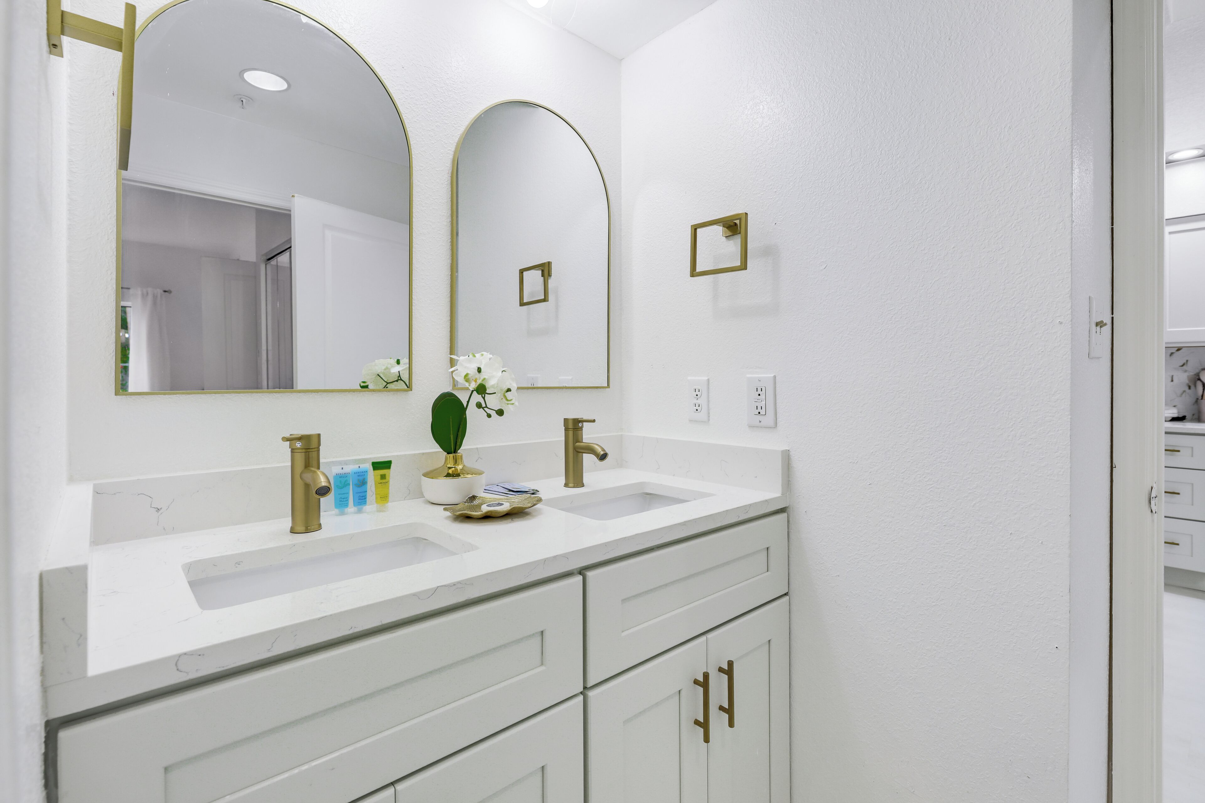Une salle de bain avec deux lavabos, un grand miroir et un meuble-lavabo avec des tiroirs.