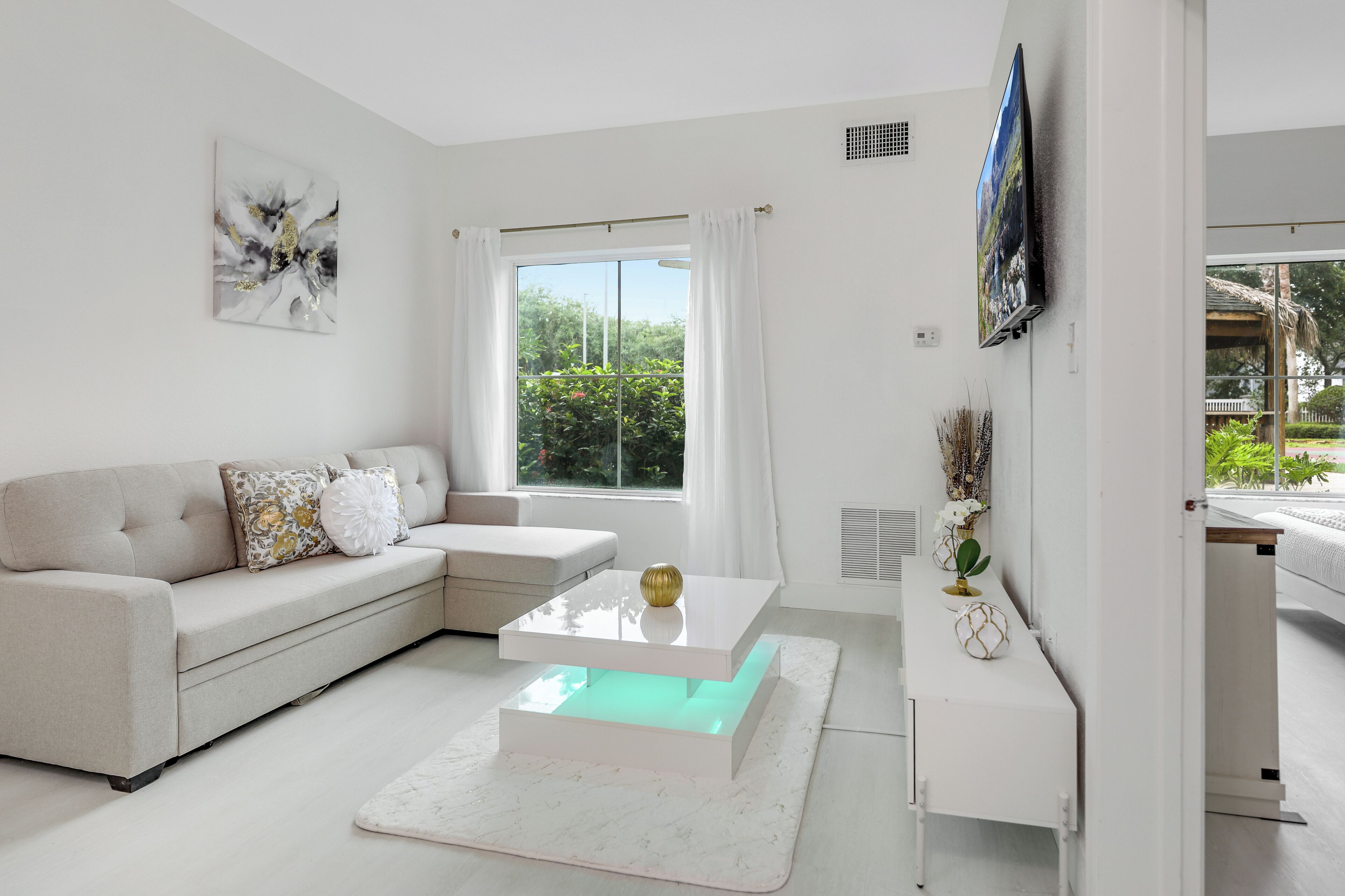 A modern living room with a sofa, a coffee table, and a TV mounted on the wall.