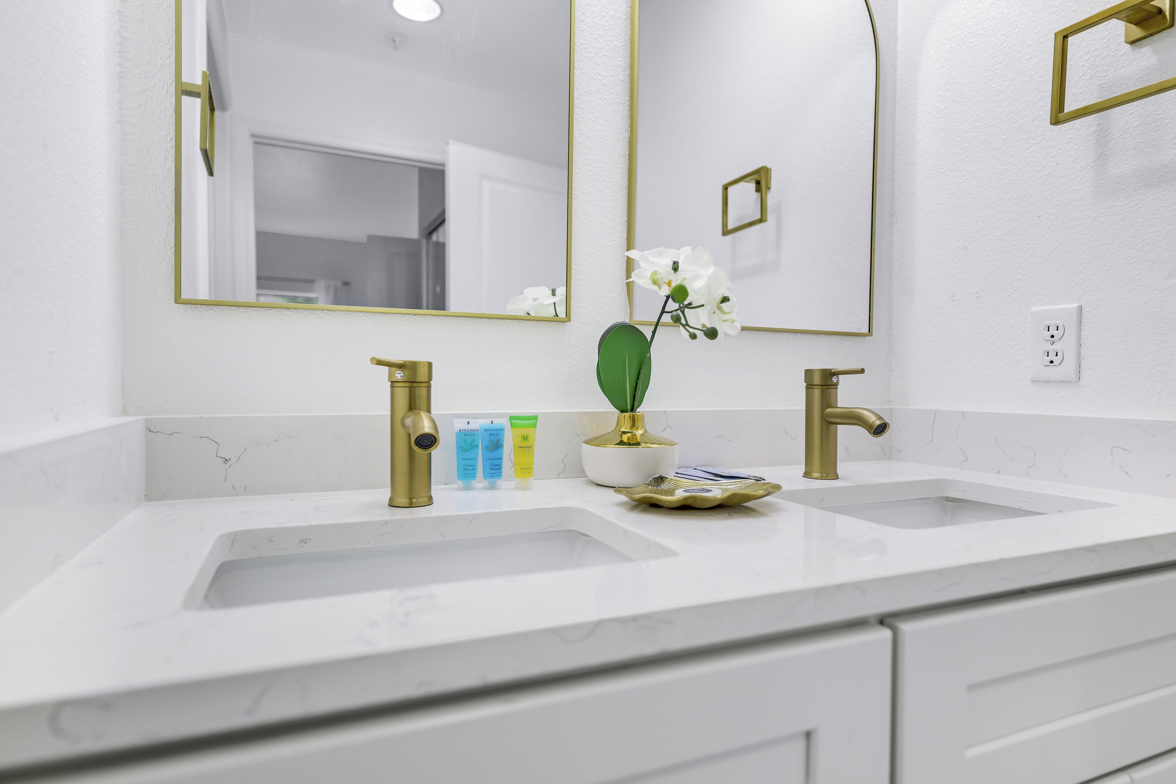 A bathroom with two sinks, a large mirror, and a potted orchid.