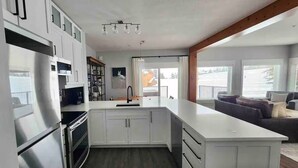 Een moderne keuken met witte kastjes, een roestvrijstalen koelkast en een groot keukenblok met een spoelbak.