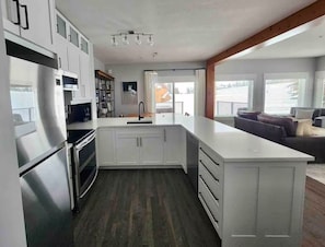 Eine moderne Küche mit weißen Schränken, einem Edelstahlkühlschrank und einer großen Kochinsel mit Spüle.