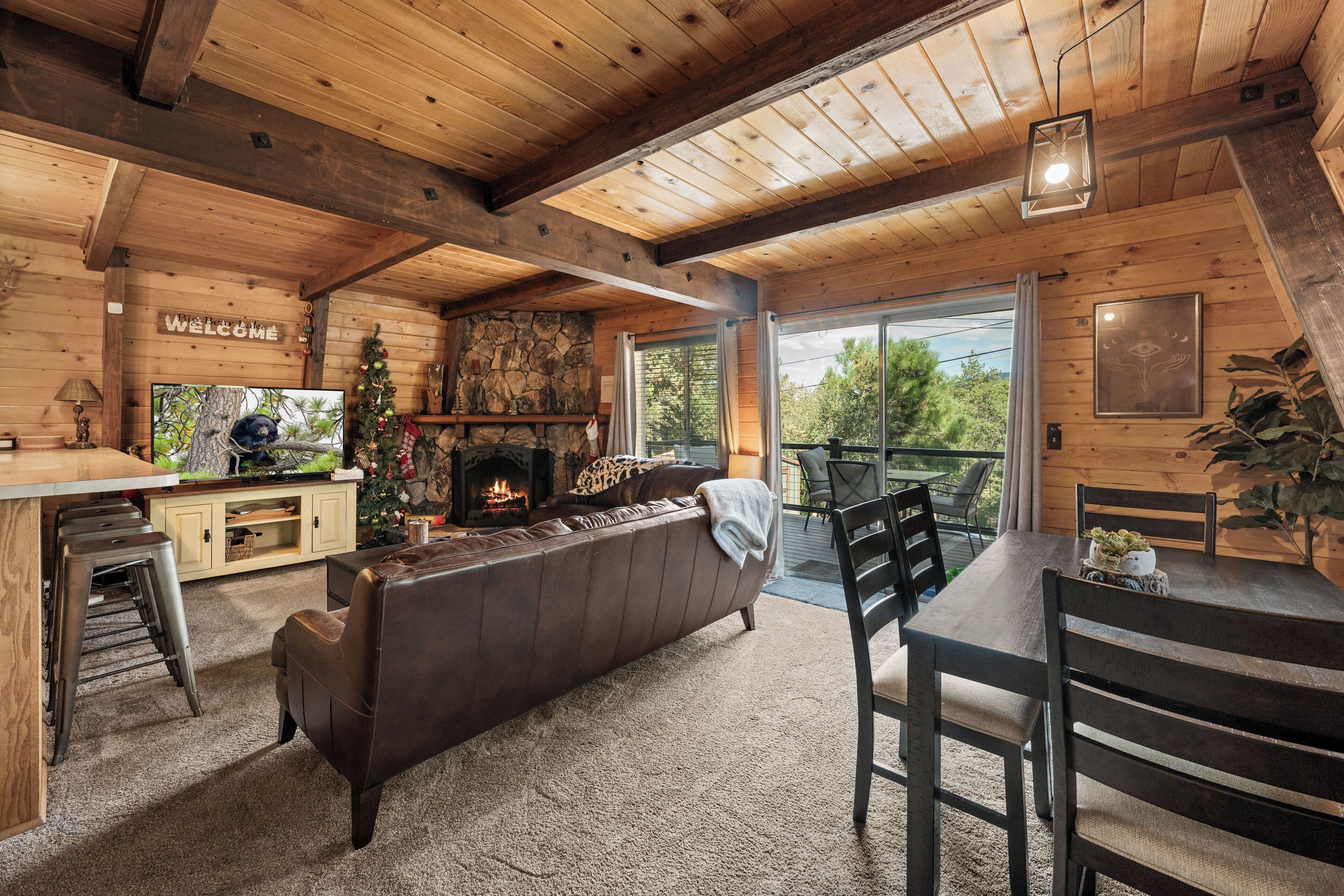 Un intérieur de chalet chaleureux avec une cheminée, un plafond en bois et un balcon offrant une vue imprenable.