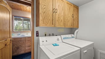 A laundry room with wooden cabinets, a washing machine, and a dryer.
