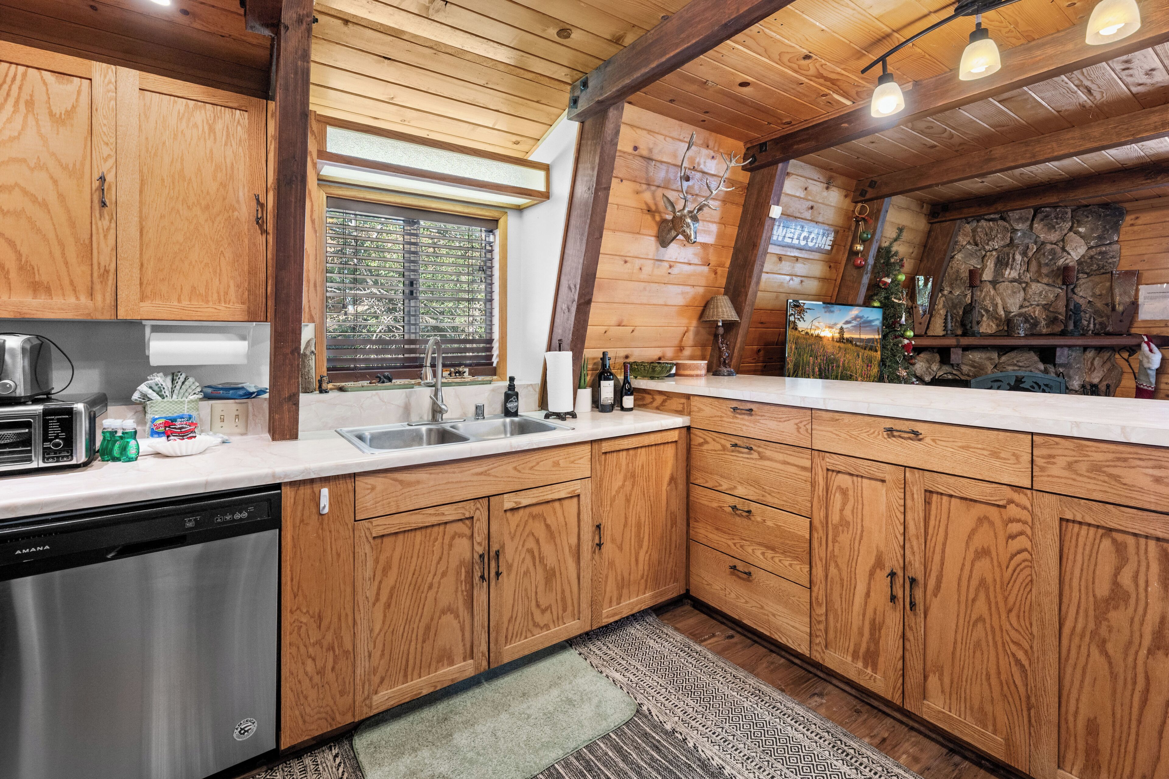 A kitchen with wooden cabinets, a dishwasher, a sink, and a window with blinds.