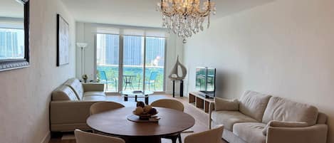 A modern living room with a chandelier, sofas, a dining table, and a television.