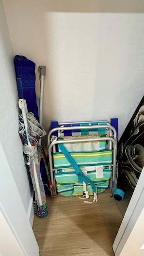 A narrow hallway with a blue and white striped bag, a blue mop, and a metal folding chair. - Lovely Condo with Intracoastal and Ocean Views! (Sunny Isles Beach)