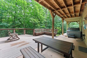 An outdoor deck with a wooden table, benches, and a grill area. - Inspiration by Blue Creek Cabins (Cleveland)