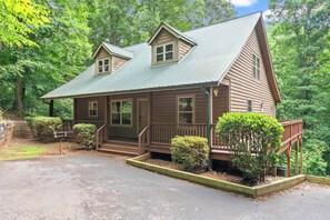 A wooden cabin with a porch, a front door, and a small staircase leading to a deck. - Inspiration by Blue Creek Cabins (Cleveland)