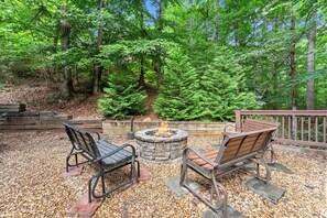 An outdoor seating area with a fire pit surrounded by a stone wall, benches, and a wooden deck. - Inspiration by Blue Creek Cabins (Cleveland)