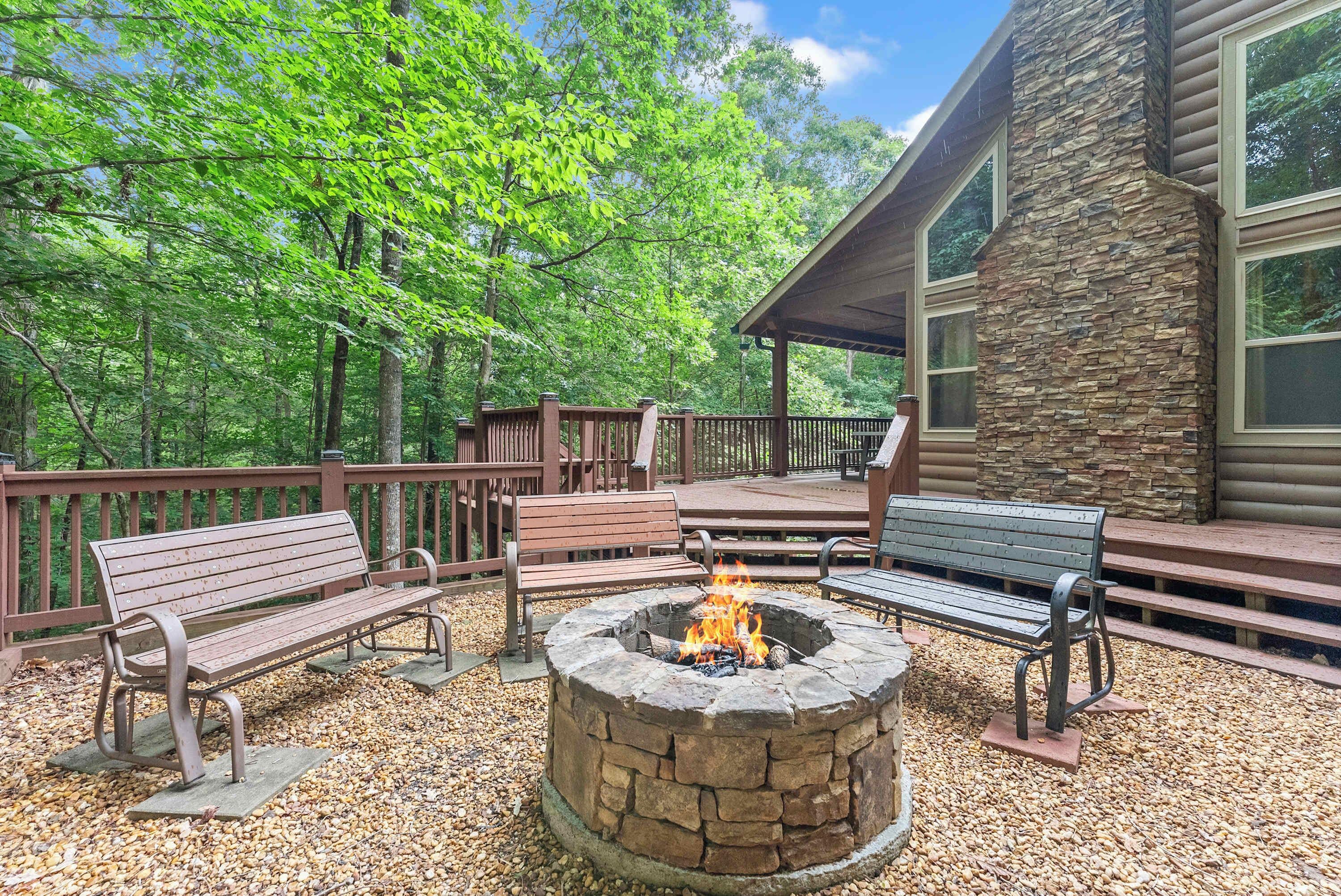 A wooden deck with benches and a stone fire pit surrounded by gravel.