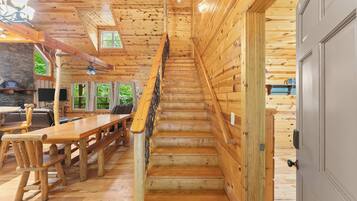 Un escalier en bois mène au deuxième étage, flanqué de murs en bois et d’un coin repas avec des bancs et des tables.