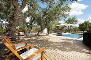 A wooden deck with lounge chairs, a pool, and a barbecue grill. - Rainbow Ranch Retreat ★ GORGEOUS 5-STAR LUXURY RANCH- STYLE HOME ★ (Wimberley)