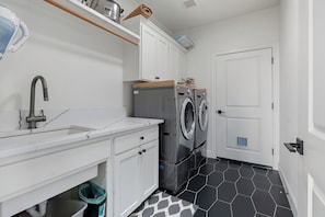 A compact laundry room with a washing machine, a sink, and a door. - Modern Family Retreat (Happy Valley)