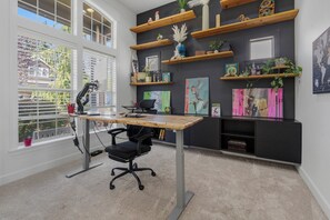 A modern office space with a desk, chair, and computer setup. There are shelves with decorative items and plants. - Modern Family Retreat (Happy Valley)