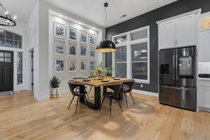 A modern kitchen with a wooden dining table, black chairs, a black pendant light, and a stainless steel refrigerator. - Modern Family Retreat (Happy Valley)