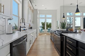 A modern kitchen with a central island, built-in appliances, and a view to the outdoors. - Modern Family Retreat (Happy Valley)