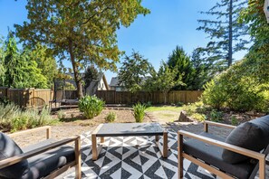 A backyard with a patio area featuring a patterned floor, two sofas, and a table. - Modern Family Retreat (Happy Valley)