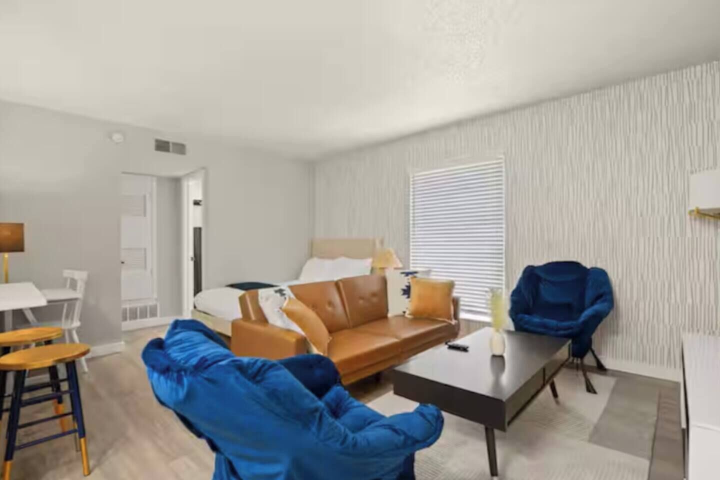 A modern living room with a sofa, a coffee table, and a dining area with chairs.